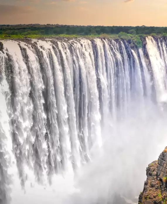 Majestic view of Victoria Falls, also called "The Smoke That Thunders," on the Zimbabwe-Zambia border, with powerful cascades plunging into misty depths of the Zambezi Gorge.