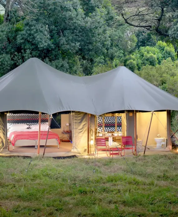 Luxurious tented suite at Angama Mara in Kenya, with vibrant interiors and scenic views over the Maasai Mara.