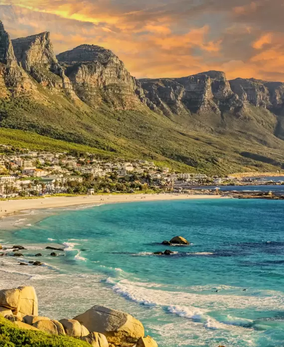 Camps Bay Beach in Cape Town, South Africa, with the iconic Twelve Apostles mountain range at sunset.