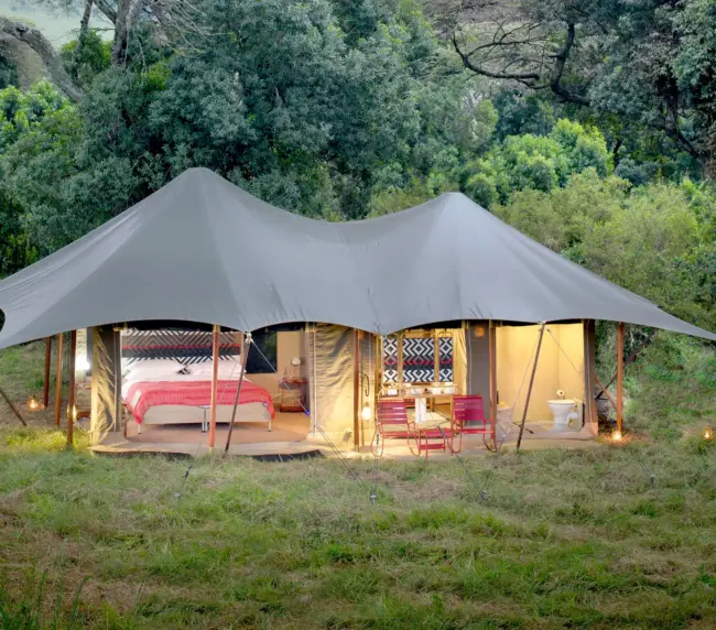 Luxurious tented suite at Angama Mara in Kenya, with vibrant interiors and scenic views over the Maasai Mara.