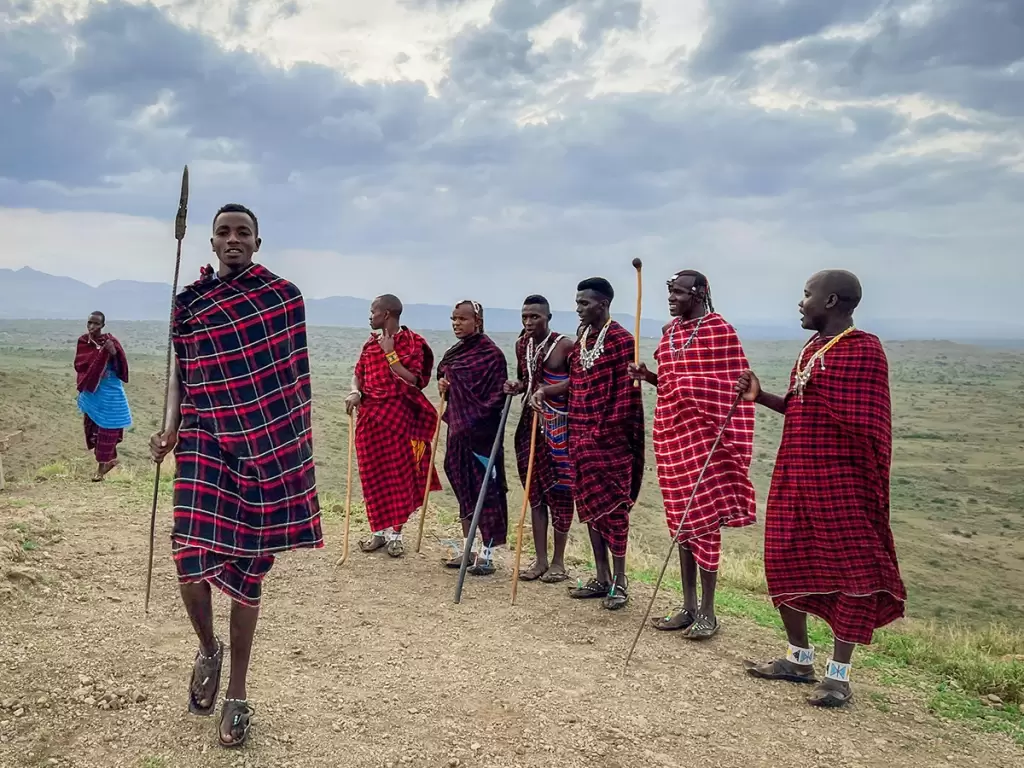 Maasai people in Arusha in traditional attire against a scenic Tanzanian backdrop.
