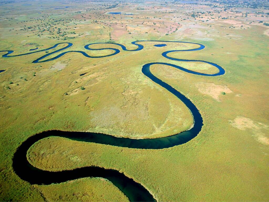 Aerial view of the winding waterways of Botswana’s Okavango Delta through the lush green floodplains.