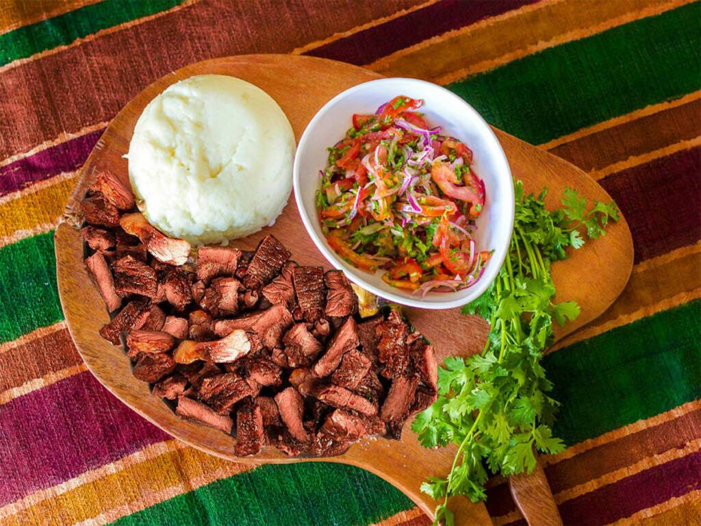 Nyama Choma – A traditional Kenyan grilled meat dish served with mashed potatoes and salad.