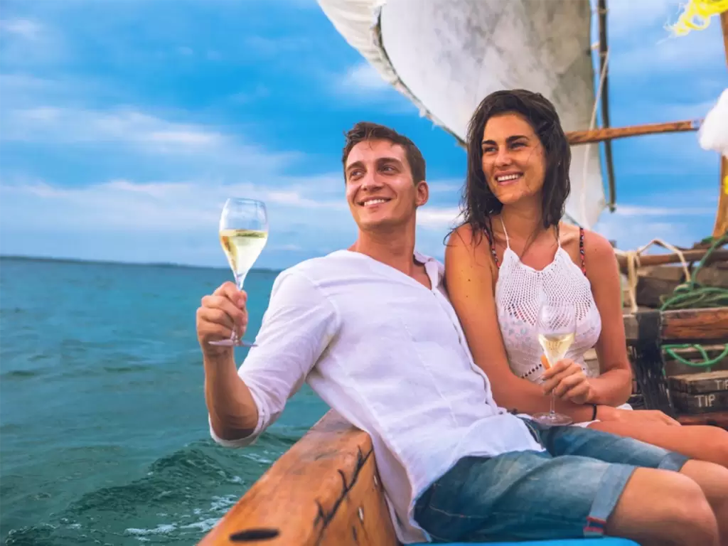 Newlyweds celebrating their luxury romantic honeymoon across African waters with champagne.