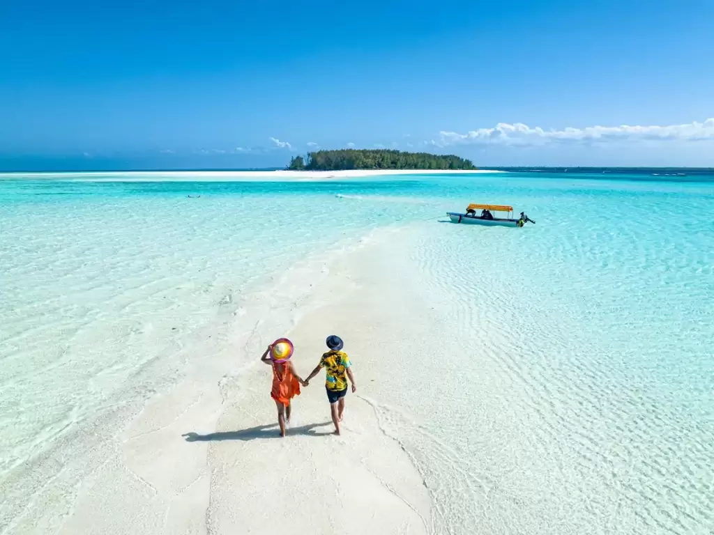 A honeymoon couple strolling across a secluded tropical sandbar in Africa.