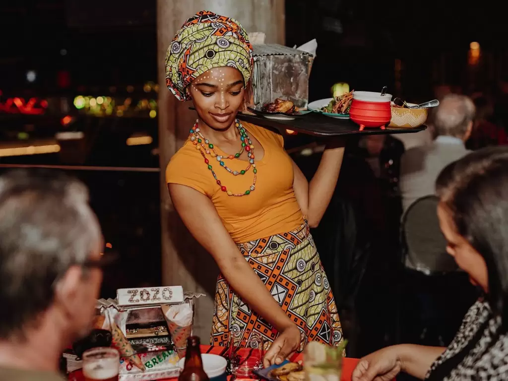 Waitress serving South African dishes at a Cape Town restaurant, highlighting the hospitality of Africa’s food scene.