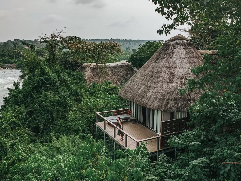 Thatched-roof luxury lodge in Uganda with a private deck nestled in lush rainforest overlooking River Nile for secluded nature escapes in Africa.
