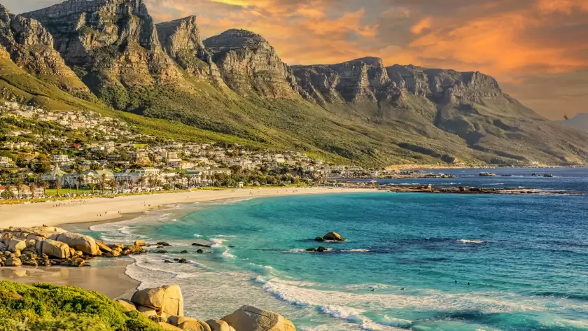 Camps Bay Beach in Cape Town, South Africa, with the iconic Twelve Apostles mountain range at sunset.