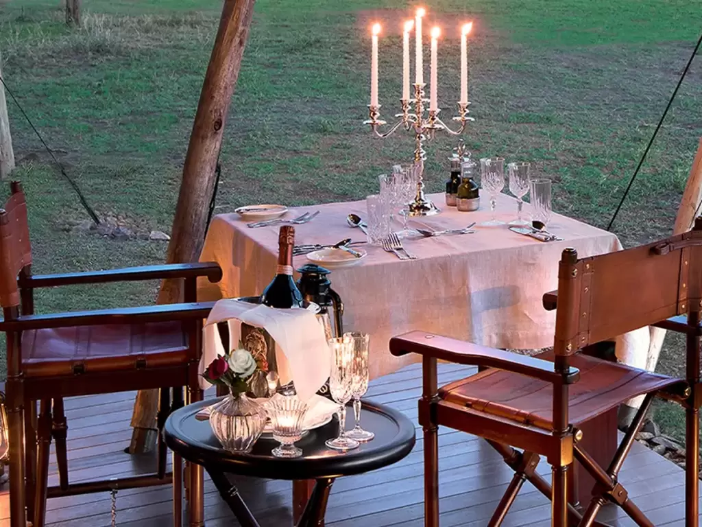 Romantic candlelit dining setup in a luxury safari tent, for a honeymoon couple in Africa. 