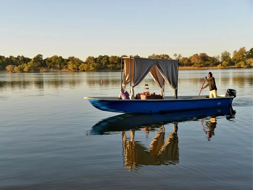 A romantic African boat high-tea with canopy drapes on a private river safari during a luxury honeymoon in Zambia.