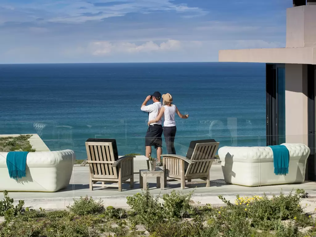 A couple overlooking turquoise ocean in South Africa from a luxury coastal terrace.