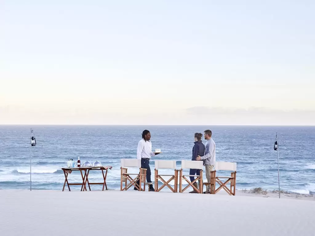 A honeymoon couple being served on a private white sandy beach in South Africa.
